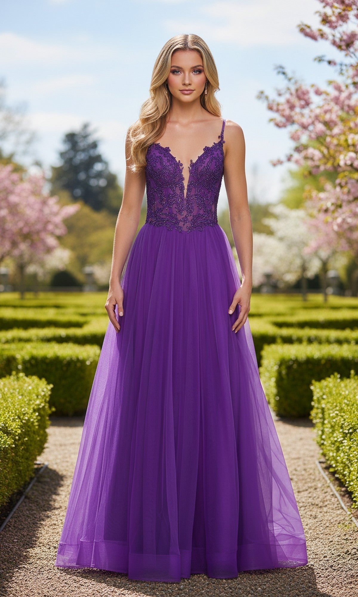 A woman wearing the La Femme 33674 Beaded-Corset Long Prom Ball Gown with a tulle skirt stands outside on a garden path lined with green hedges and blossoming trees.